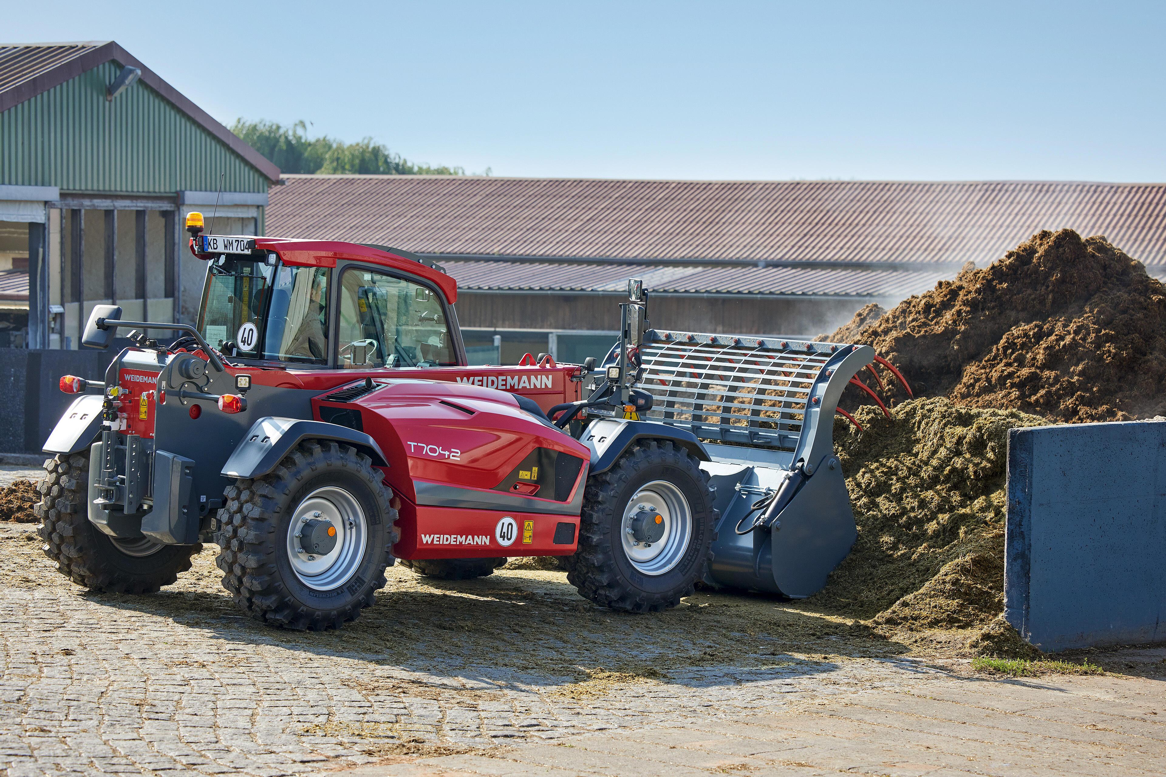 Weidemann telehandler T7042 in use with grab bucket at the manure heap