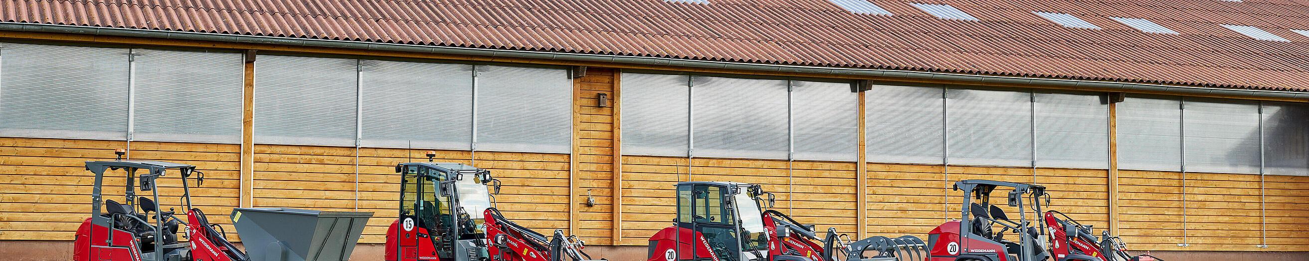 Diferentes Hoftrac de Weidemann se encuentran delante de una instalación agrícola