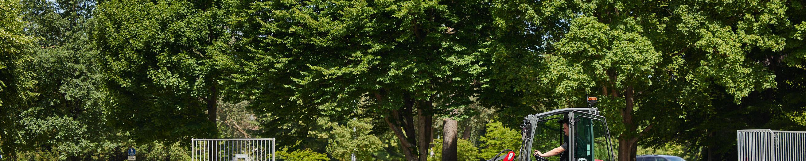 Hoftrac 1190e con cabina de Weidemann en el parque de una ciudad con barredora