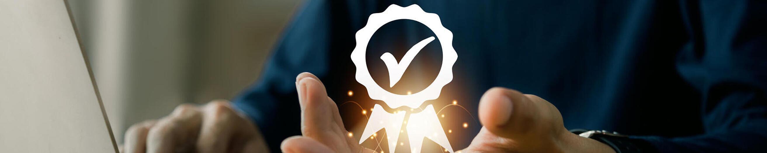 Una persona está sentada delante de un ordenador portátil y levanta la mano